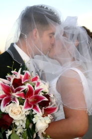 bride and groom kissing with wedding bouquet